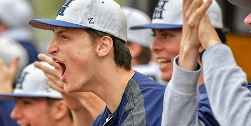 Male baseball team cheering from the dugout